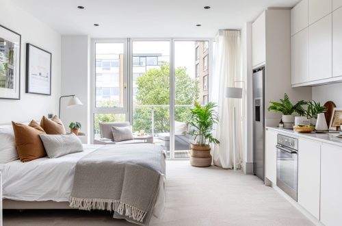 London studio flat interior, compact open-plan layout, neutral-toned carpeted floor
